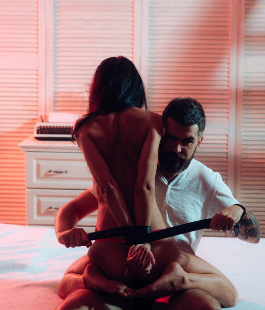 Sexy Dirty Talk in Night time. Sexy couple in bed. Bondage and bdsm concept. Strapped hands - satisfaction. Passionate naked woman and man in underwear pants. Sexually Harassing woman. Dominant man. - 写真・画像