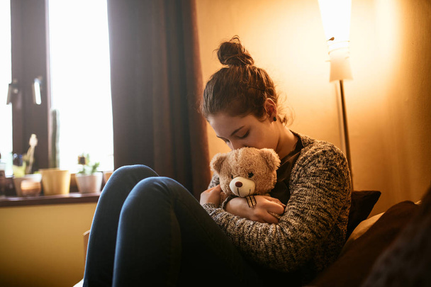 Πορτρέτο του ένα θλιβερό εφηβικό κορίτσι που αγκαλιάζει ένα αρκουδάκι. - Φωτογραφία, εικόνα