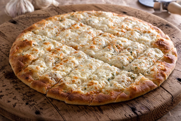 Delicious garlic fingers with herb butter and melted mozzarella cheese on a rustic wooden board. - Photo, Image