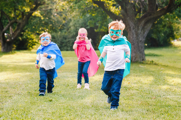 Bonito adorável pré-escolar crianças caucasianas jogando super-heróis. Três crianças amigos se divertindo juntos e correndo ao ar livre no parque. Feliz infância ativa e conceito de amizade
.  - Foto, Imagem