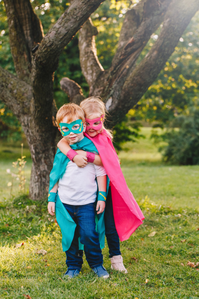Cute adorable preschool Caucasian children playing superheroes. Two kids friends hugging together outdoors in park. Happy active childhood and friendship concept.  - Foto, Imagen