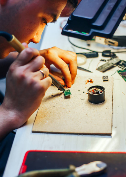 jovem adolescente soldar circuito de computador com ferro de solda em casa. brasagem
 - Foto, Imagem