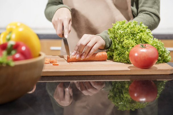 Vista da vicino delle verdure tagliate a mano dalla donna con coltello in cucina
 - Foto, immagini