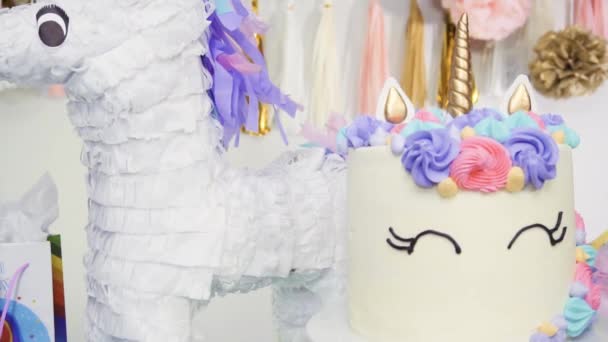 En cámara lenta. Mesa de fiesta de cumpleaños de niña con pastel de unicornio, cupcakes y galletas de azúcar
 - Metraje, vídeo