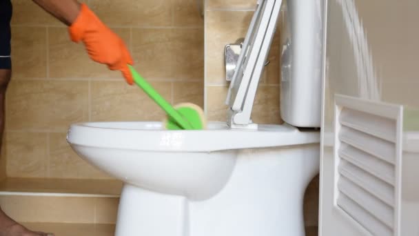 Hand van een man met oranje rubberen handschoenen wordt gebruikt om polijsten om te zetten in een toilet. - Video