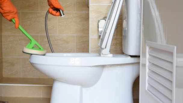 Turuncu lastik eldiven giyen bir adamın elini bir tuvalete parlatma dönüştürmek için kullanılır. - Video, Çekim