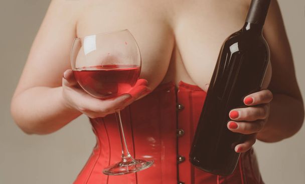 Sexy Plus Size Lingerie. Sexy zijn. Vrouw in het rood glas wijn houden. XXL groot formaat. Vrouwelijke borst. Mooi meisje toont haar prachtige borsten. - Foto, afbeelding