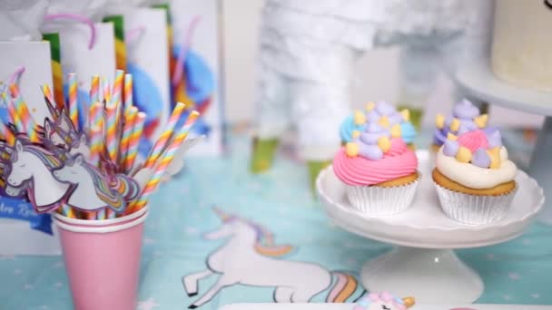 Primer plano de la mesa de la fiesta de cumpleaños de la niña con pastel de unicornio, magdalenas y galletas de azúcar
. - Metraje, vídeo