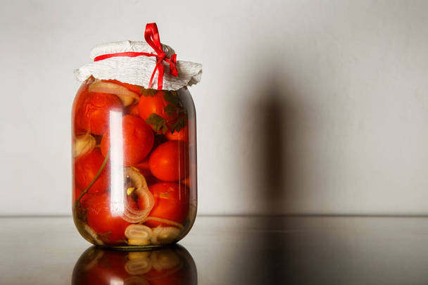 one standard big glass jar with homemade canned tomatoes stand on kitchen table against gray wall background - Φωτογραφία, εικόνα