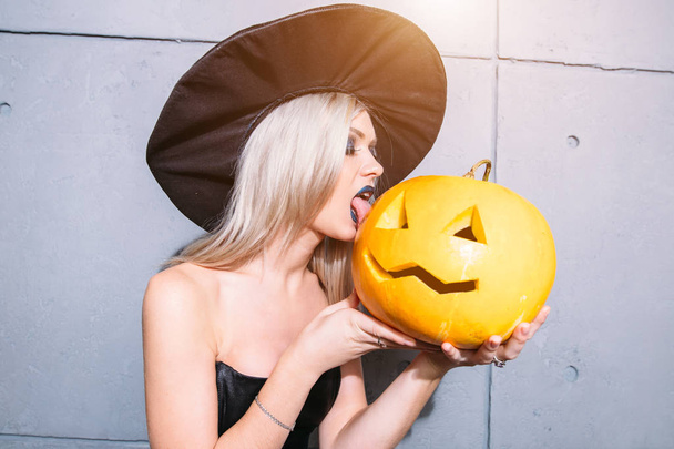 Young blonde woman holding pumpkins for halloween - Фото, зображення