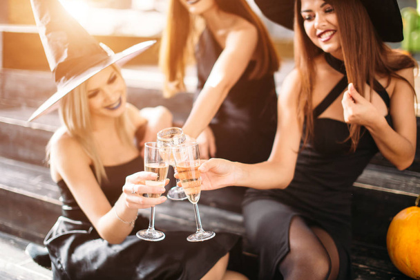 Three girls sit and clink glasses with champagne - Fotografie, Obrázek