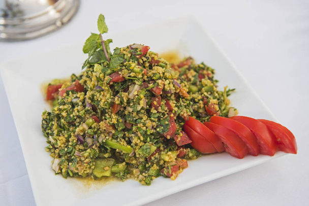 Здоровое вегетарианское блюдо из кускуса в ресторане с помидорами на белой тарелке
 - Фото, изображение