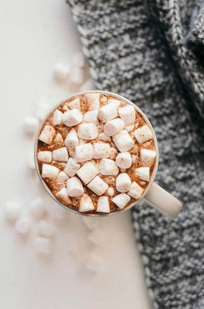 Horké kakao s marshmallow, skořici a koření, teple útulné přehoz na bílém stole. Pohled shora. - Fotografie, Obrázek