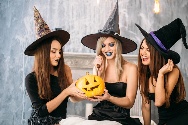 Three adult women carve Halloween pumpkins while laughing and having a party - Foto, Imagem