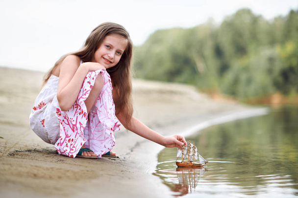 nehirde gemi yelken bir oyuncakla oynayan kız - Fotoğraf, Görsel