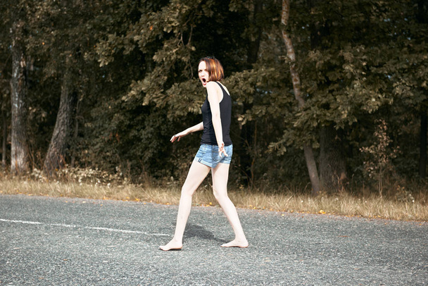 mladá dívka chůze naboso na silnici, pojem léto a cestování - Fotografie, Obrázek