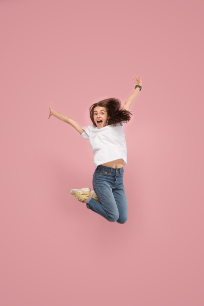 Freedom in moving. Pretty young woman jumping against pink background - Fotografie, Obrázek