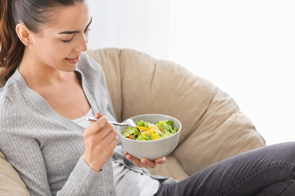 Fiatal nő eszik friss saláta otthon. Egészséges élelmiszer koncepció - Fotó, kép