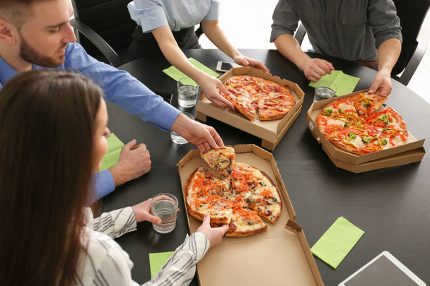 若い人はオフィスでテーブルで食べるピザ - 写真・画像