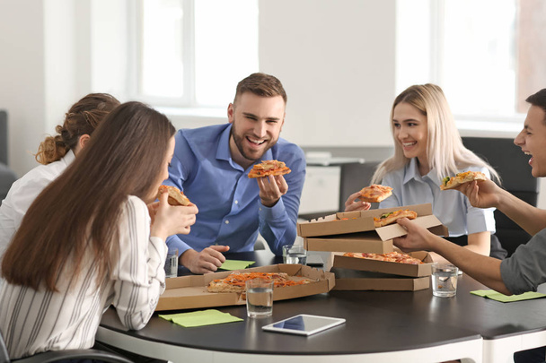 若い人はオフィスでテーブルで食べるピザ - 写真・画像