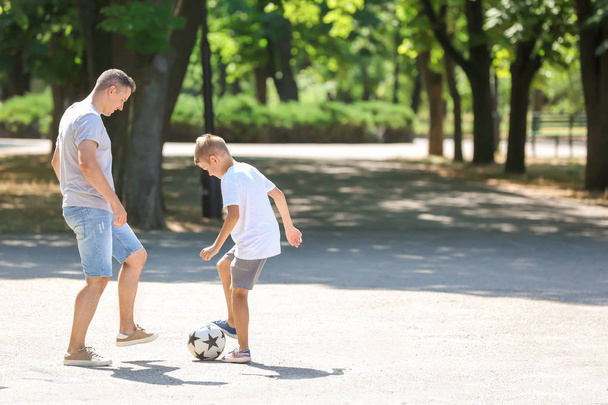 Pieni poika isänsä kanssa pelaamassa jalkapalloa ulkona
 - Valokuva, kuva