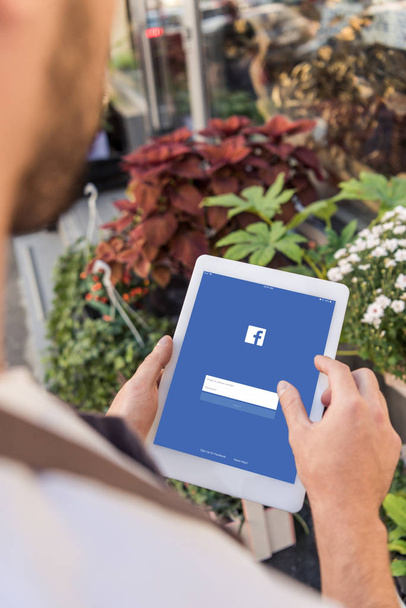 cropped image of florist using tablet with loaded facebook page near flower shop - Fotó, kép