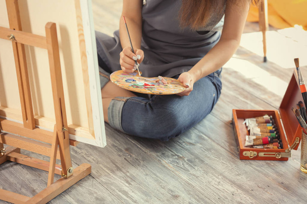 Female artist painting picture in workshop - 写真・画像