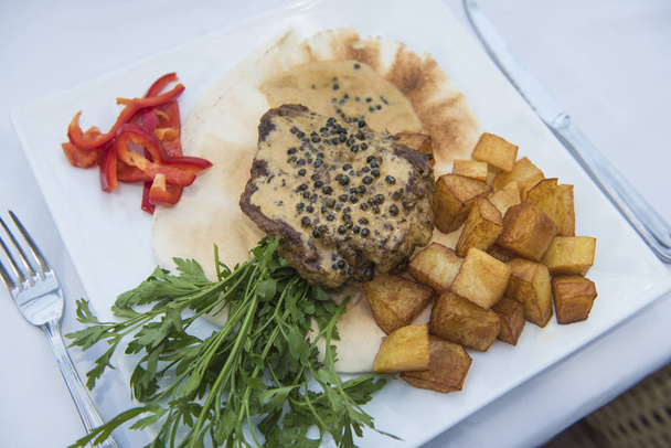 Крупный план бифштекса из говяжьего филе в перцовом соусе в роскошном ресторане на открытом воздухе
 - Фото, изображение