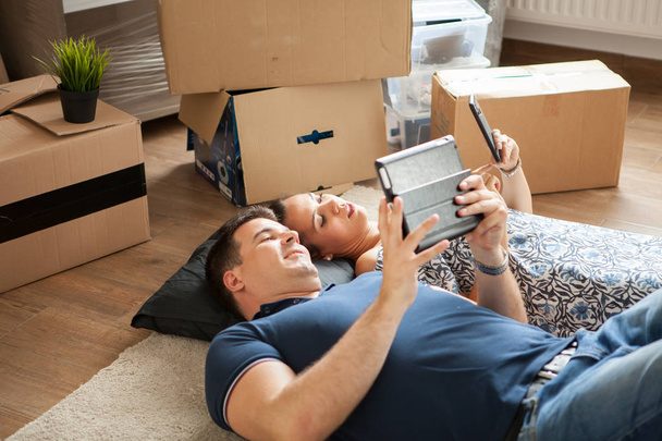 Happy young couple lying on floor near moving boxes. - Zdjęcie, obraz