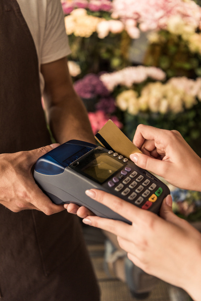 обрезанное изображение клиента, оплачивающего цветы кредитной картой в магазине
 - Фото, изображение