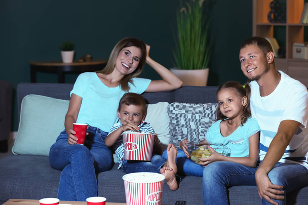 Szczęśliwa rodzina jedzenie popcorn podczas oglądania telewizji w godzinach wieczornych - Zdjęcie, obraz