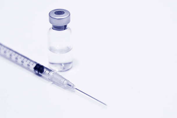 Flacon de médicament ou de vaccin et seringue en plastique de 1 ml avec aiguille isolée sur le fond blanc, couleur bleu
 - Photo, image