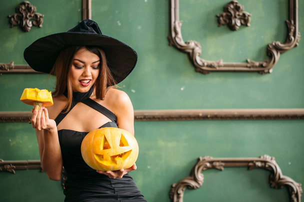 Halloween. Sexy lady in red with big pumpkin on her hands - Фото, зображення
