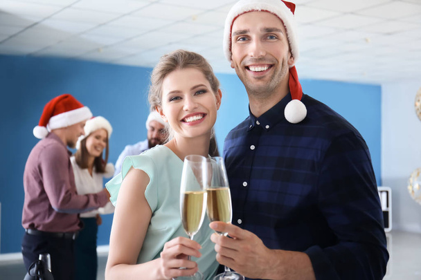 Jongeren met een glas champagne vieren Kerstmis op bedrijfsfeest in het kantoor - Foto, afbeelding