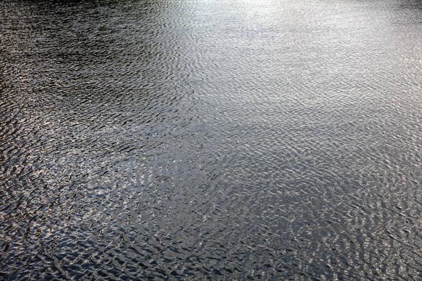 Φόντο πόλη ποτάμι νερού το απόγευμα. Κυματιστό σκούρα επιφάνεια με αντανακλάσεις - Φωτογραφία, εικόνα