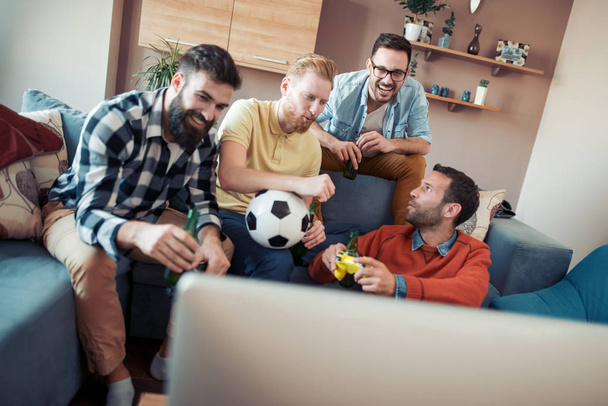 Щасливі друзі-чоловіки розважаються вдома, дивлячись футбол по телевізору
 - Фото, зображення