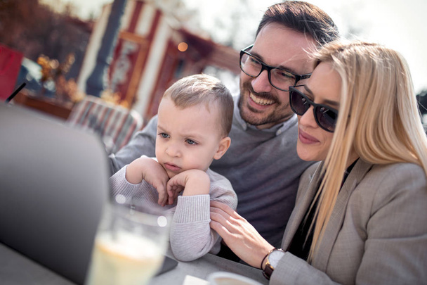 Happy young parents with their sweet boy in outdoors cafe. - Фото, зображення