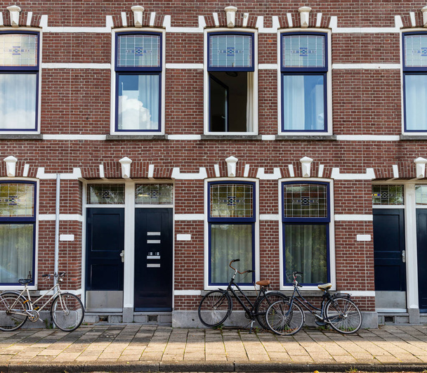 Rotterdam, Holandia. Rowery, przed tradycyjnym z czerwonej cegły domy z windows niebieski tło. - Zdjęcie, obraz
