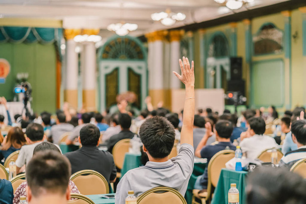 Задний вид аудитории, показывающей руку, чтобы ответить на вопрос спикера на сцене в конференц-зале или семинаре, бизнес и образовательная концепция
 - Фото, изображение