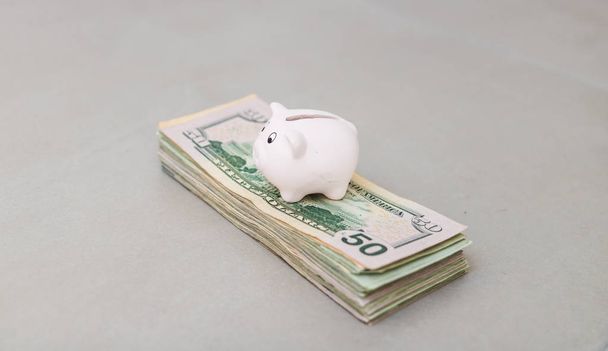 superfície cinzenta da tabela com o banco Piggy e dólares americanos
 - Foto, Imagem