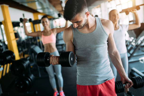 fitness, sport, training, gym and lifestyle concept - group of smiling people working out with dumbbells in the gym - 写真・画像