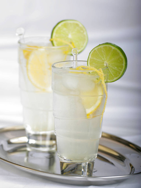 cold summer drink with lemon and lime in glasess on silver tray, close-up  - 写真・画像