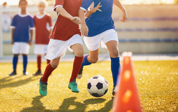 Εκπαίδευση ποδοσφαίρου. Νεαρούς ποδοσφαιριστές που τρέχουν με τη μπάλα. Αγόρια κλοτσιές μπάλα ποδοσφαίρου. Ποδόσφαιρο νεολαίας ομάδες παίζουν υπαίθρια ποδοσφαίρου τουρνουά. Γήπεδο ποδοσφαίρου στο παρασκήνιο - Φωτογραφία, εικόνα