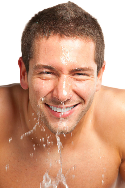 Young man spraying water on his face after shaving in the bathroom - Φωτογραφία, εικόνα