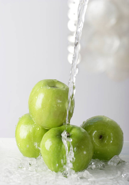 water pouring on pile of green apples, close-up   - 写真・画像