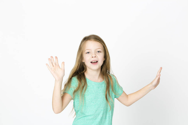 happy beautiful little blonde girl in green t-shirt dancing on white studio background  - Фото, изображение