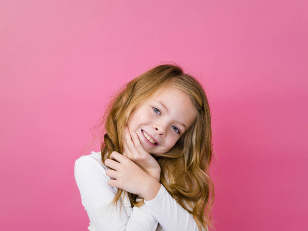 portrait of happy satisfied girl in white clothes standing and looking at camera with toothy smile on pink background  - Photo, Image