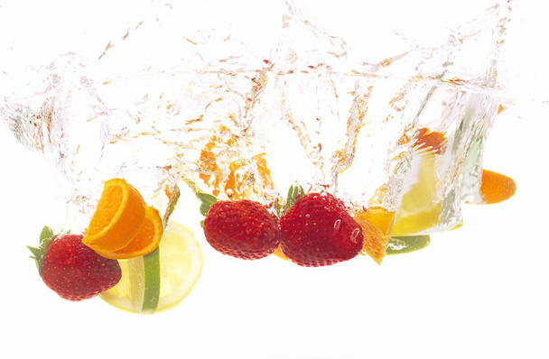 reife rote Erdbeeren mit Orangen- und Zitronenscheiben, Limette fällt auf Wasser, Nahaufnahme   - Foto, Bild