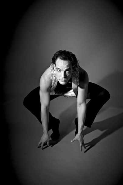 Flexibler männlicher Tänzer führt modernen Tanz im dunklen Studio auf  - Foto, Bild