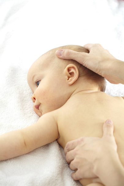 Young woman massaging seven month old baby  - Fotó, kép